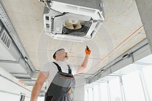 Worker repairing ceiling air conditioning unit