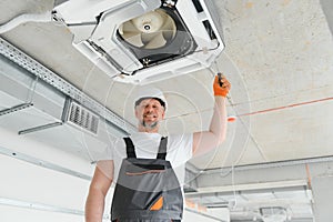 Worker repairing ceiling air conditioning unit