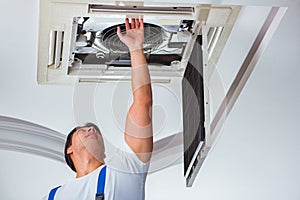 The worker repairing ceiling air conditioning unit