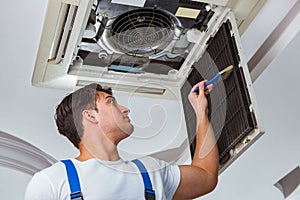 The worker repairing ceiling air conditioning unit