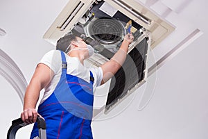 The worker repairing ceiling air conditioning unit