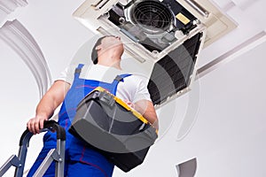 The worker repairing ceiling air conditioning unit