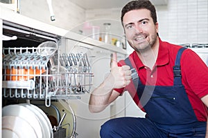 Worker repairing dishwasher in the kitchen