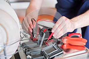 Worker repairing the dishwasher in the kitchen