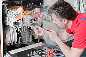 Worker repairing the dishwasher in the kitchen