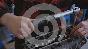 A worker repairing the engine of a car to the service center. Close-up of the equipment in the room. A man with dirty