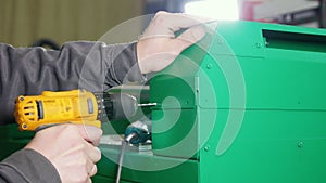 Worker repairing a machine at the factory using a hand drill