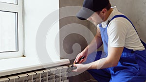 Worker repairing radiator with wrench. Removing air from the radiator and fixing a heating problem. Dismantling and