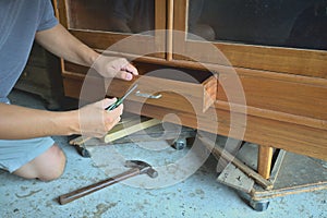 Worker repairing wooden drawers, old cabinets with screwdrivers, wooden hammers. Old wooden cabinet background. Asian worker