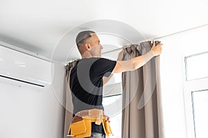 worker repairman hanging and fixing the curtain on the window