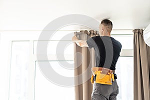 worker repairman hanging and fixing the curtain on the window