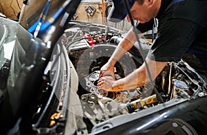 Worker, repairman wearing cap, repairing car engine.