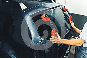 Worker replacing windscreen of car in a service station windshield replacement