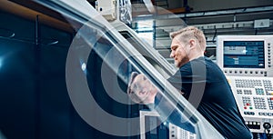 Worker resetting a cnc lathe machine in manufacturing factory