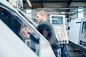 Worker resetting a cnc lathe machine in manufacturing factory