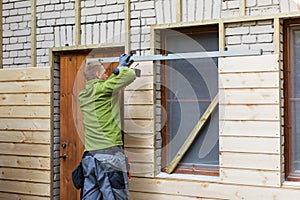 Worker restoring old brick house facade with new wooden planks