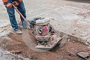 Worker reversible plate compactor on a roadwork site. photo