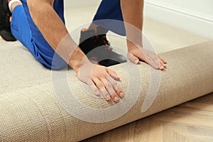 Worker rolling out new carpet flooring indoors, closeup