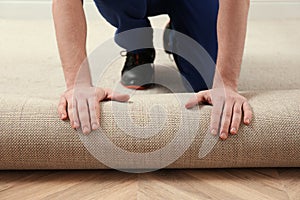 Worker rolling out new carpet flooring indoors, closeup