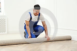 Worker rolling out new carpet in room