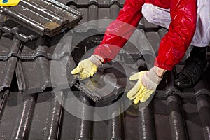 Worker on roof fixing roof tiles