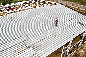 A worker on the roof mounts panels. Construction of a frame building. Top view