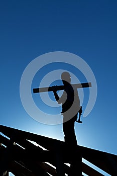 Worker on roof structure of building backlit by the setting sun