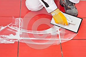 Worker with rubber trowel applying grout tile photo