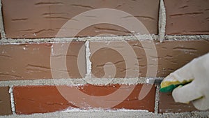 A worker rubbing seams on a brick wall while building a house. Grouting in a brick wall. Apply cement. Construction workers in