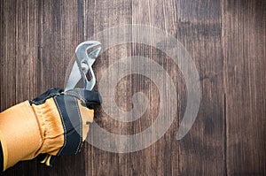 worker\'s gloved hand holds a pliers tool on a wooden background