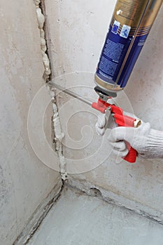 Worker's hand fix a rent in wall using polyurethane foam