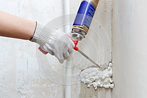 Worker's hand fix a rent in wall using polyurethane foam