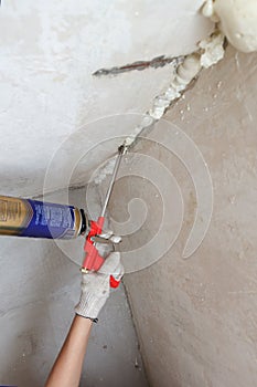 Worker's hand fix a rent in wall using polyurethane foam