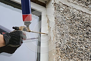 Worker's hand fix a window by polyurethane foam