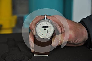 worker's hand holds a dial gauge for measuring the hardness