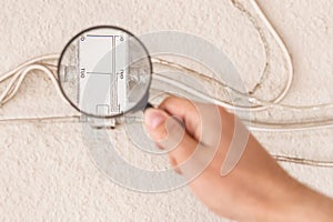 A worker`s hand inspects a large antenna splitter with a magnifying glass, close-up