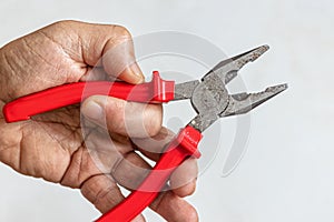 In the worker`s hand are pliers with red handles