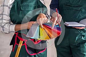 Worker`s hands choosing color for painting on sampler