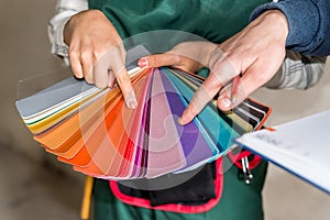 Worker`s hands choosing color for painting on sampler