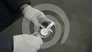 Worker's hands measure thickness of pipe with caliper at the factory.