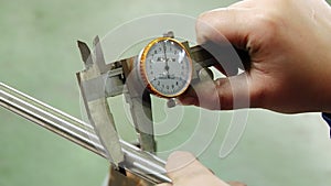 Worker's hands measure thickness of pipe with caliper at the factory.