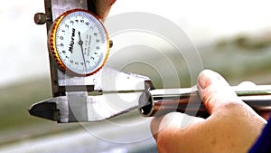 Worker's hands measure thickness of pipe with caliper at the factory.