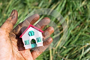 Worker\'s hands picking nuts, colored by the peel with a litle dream house