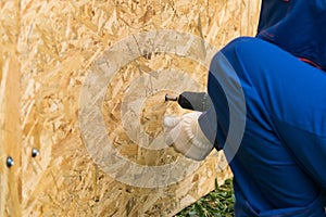 Worker`s hands screwed a wooden shield with a screwdriver, close-up