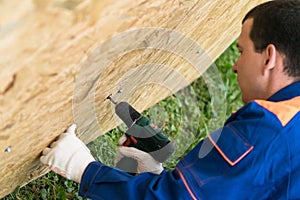 Worker`s hands screwed a wooden shield with a screwdriver, close-up top view