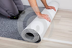 Worker`s Hands Unrolling Carpet On Floor