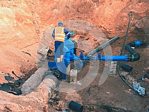 Worker in safety clothes drive valve conduit on City potable water pipe