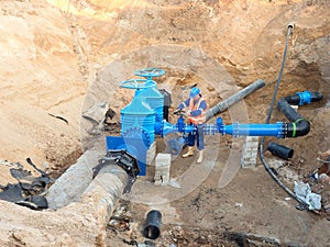 Worker in safety clothes drive valve conduit on City potable water pipe