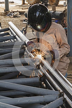 Worker with safety equipment and protective mask welding steel.