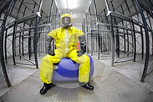 Worker in safety - protective uniform,sitting on barrel